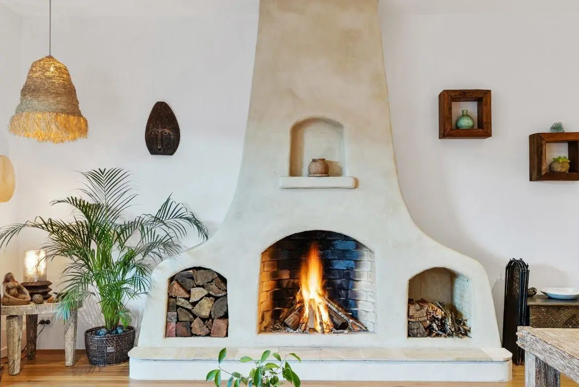 Curved white fireplace with a lit fire and timber storage niches